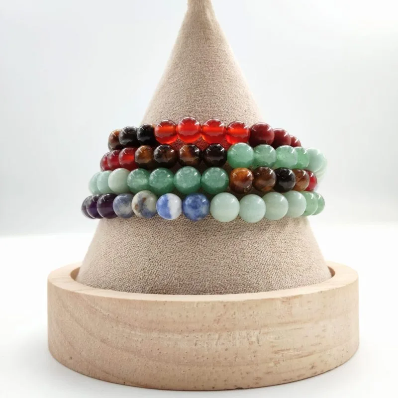 Cône présentoir en tissu beige et bois, orné de plusieurs bracelets en pierres naturelles. On distingue des perles rondes de différentes couleurs : rouge, brun, vert, bleu, violet et turquoise, créant un assortiment harmonieux et coloré.