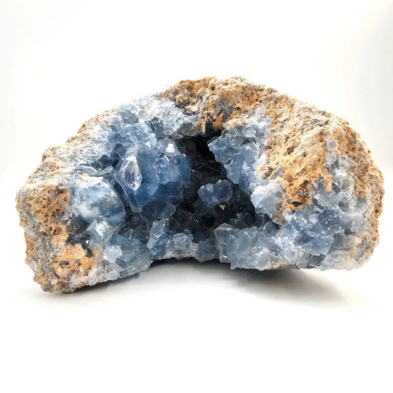 Géode de célestine naturelle, aux cristaux bleu ciel translucides formés à l’intérieur d’une gangue rocheuse beige. Les cristaux brillent par leur éclat vitreux et leur douceur apaisante.