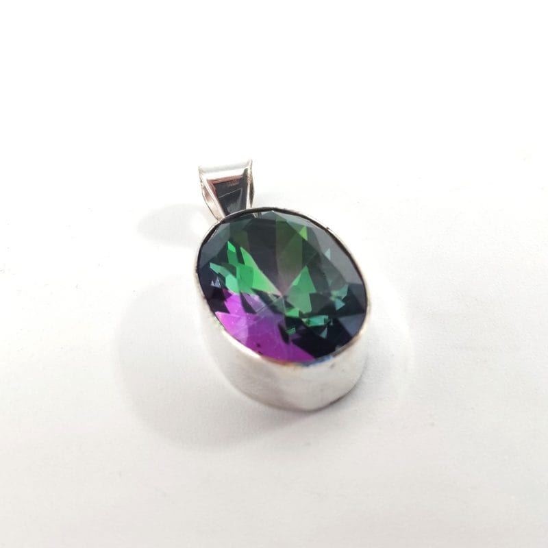 Pendentif en argent serti d’une pierre ovale facettée aux reflets multicolores vert, violet et bleu, posé sur fond blanc.