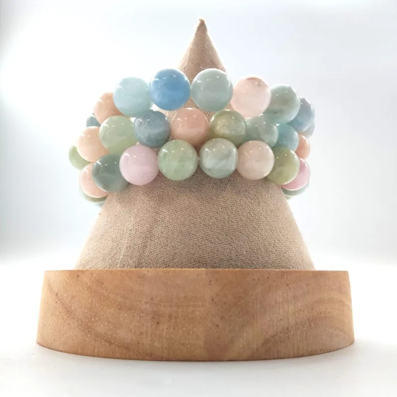 Cette image met en valeur un bracelet composé de perles rondes de la famille des Béryls, incluant des nuances douces de Morganite (rose poudré), d'Aigue-marine (bleu pastel) et d'Héliodore ou Béryl vert (vert d'eau). Les perles, d'un diamètre généreux d'environ 8 à 10 mm, possèdent un fini parfaitement lisse et un éclat mat-satiné qui donne au bijou une allure sophistiquée et apaisante.