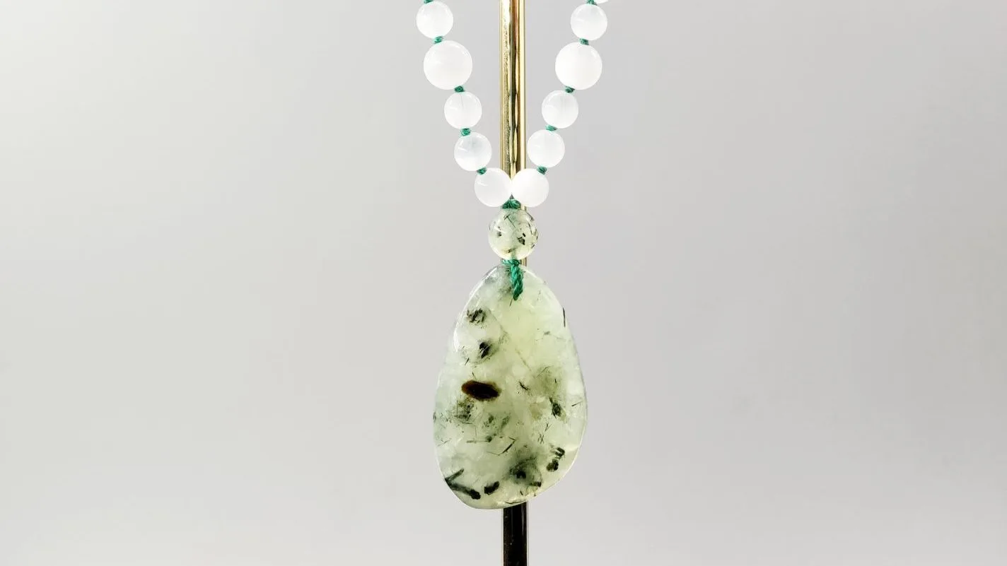 Pendentif en pierre naturelle de Prehnite avec inclusions noires, monté sur un collier de perles blanches translucides, rechargé par la lumière des pleines lunes en 2026