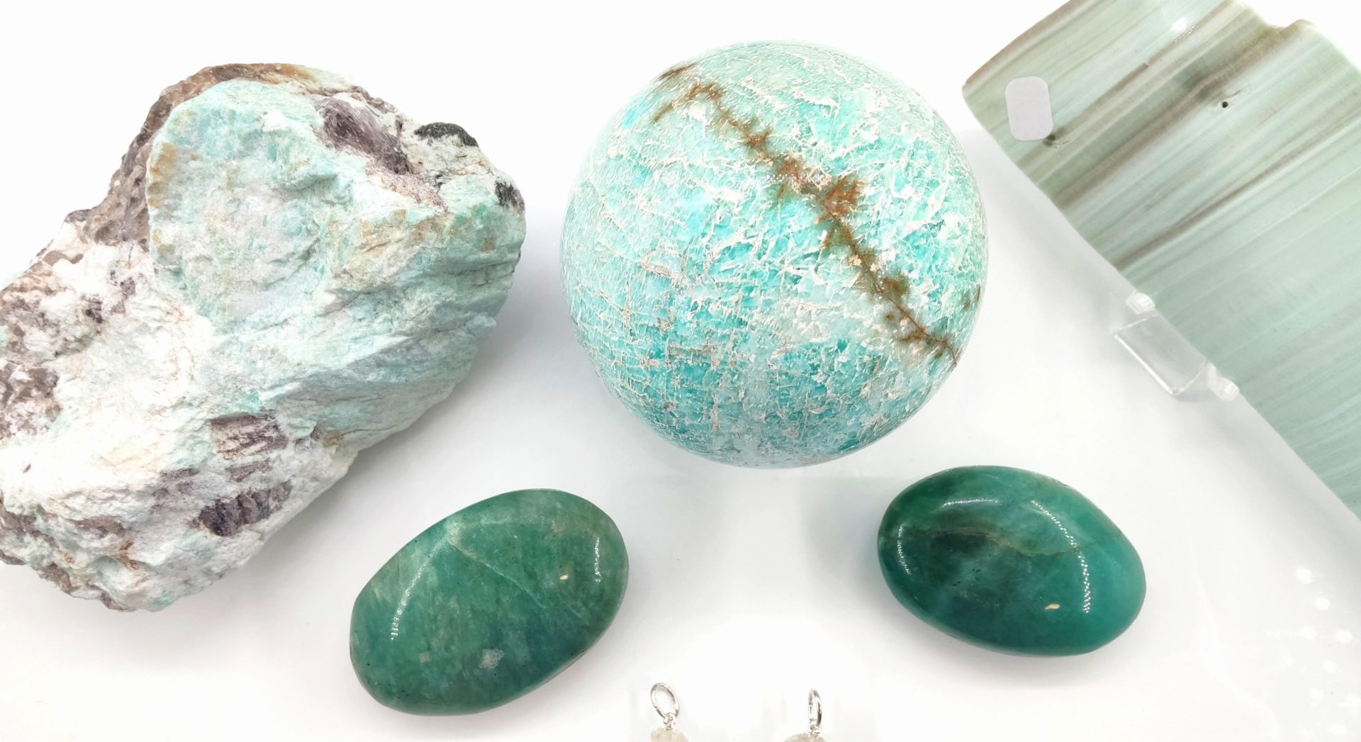 Un assortiment de pierres naturelles dans des tons vert menthe, turquoise et émeraude, contrastant sur un fond blanc uni.