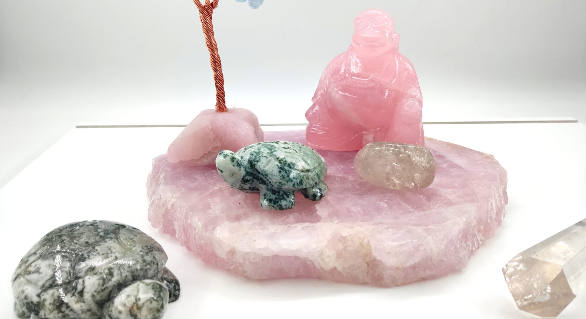 Un ensemble d'objets centrés sur le quartz rose et des figurines animales, disposés sur un plateau en pierre rose brute.