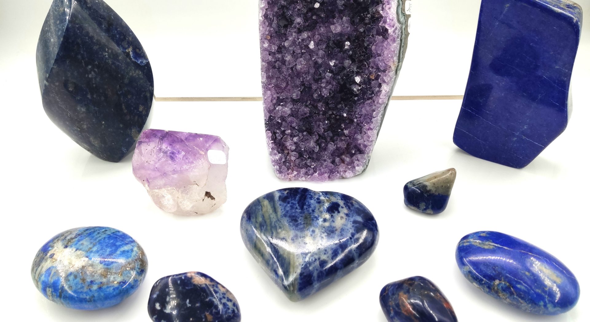 Divers cristaux et pierres polies dans des tons de bleu azur, bleu marine et violet royal sur fond blanc